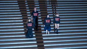No Putin No War: Drei Mitglieder der russischen Band Pussy Riot treten in der Pinakothek der Moderne in München mit einer deutlichen Botschaft auf. Als zweiter von links steht der österreichische Künstler Wolfgang Flatz. Foto: Peter Kneffel/dpa